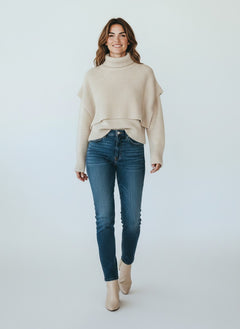 BubiniSegreti beiger Strickpullover mit Rollkragen und zweilagigem Design, kombiniert mit blauer Jeans