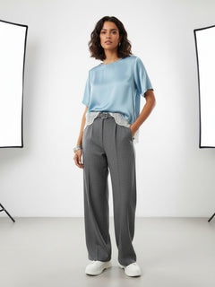 BubiniSegreti Damenbluse aus blauem Satin mit asymmetrischem Saum und cremeweißer Spitze, getragen von einem Model