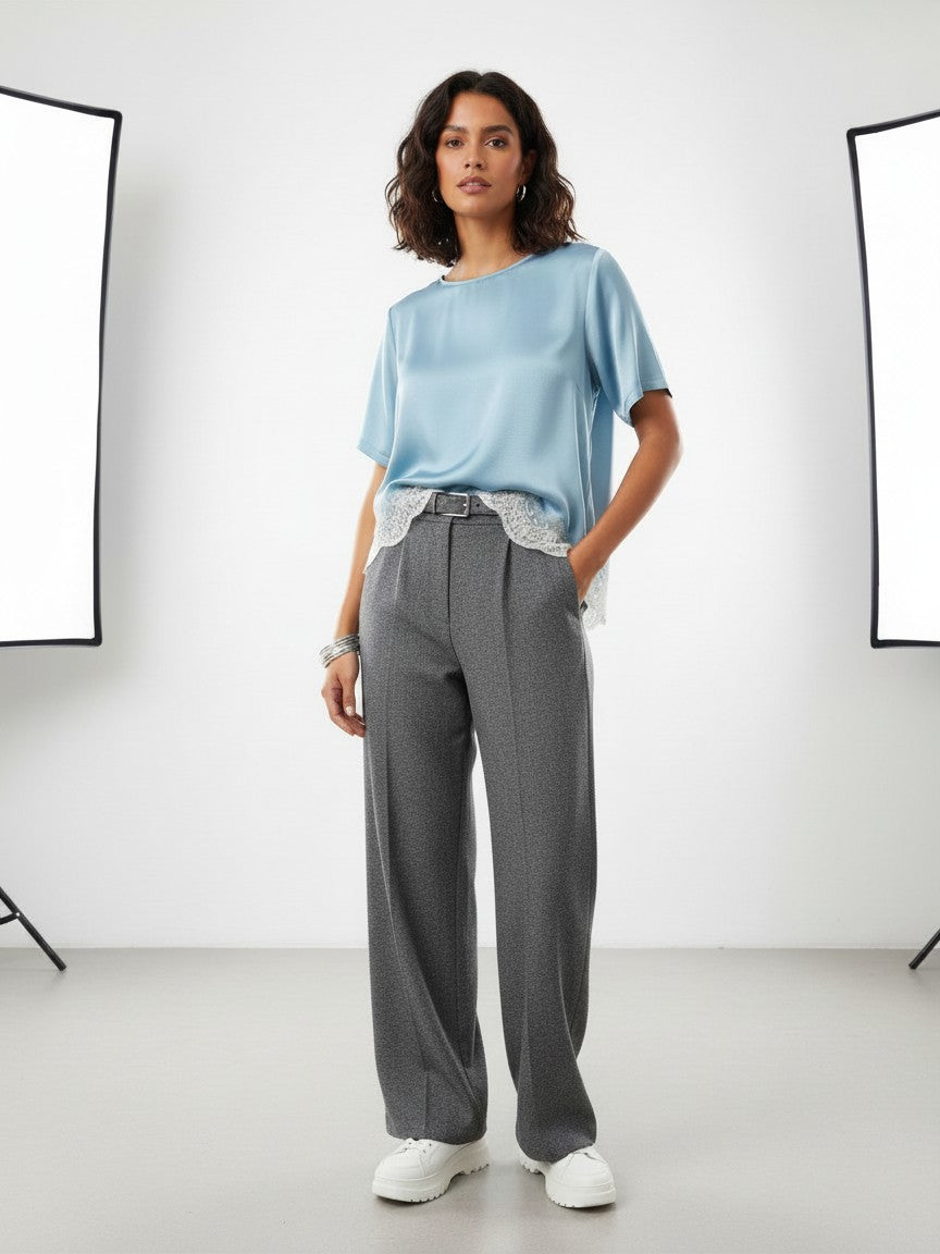 BubiniSegreti Damenbluse aus blauem Satin mit asymmetrischem Saum und cremeweißer Spitze, getragen von einem Model