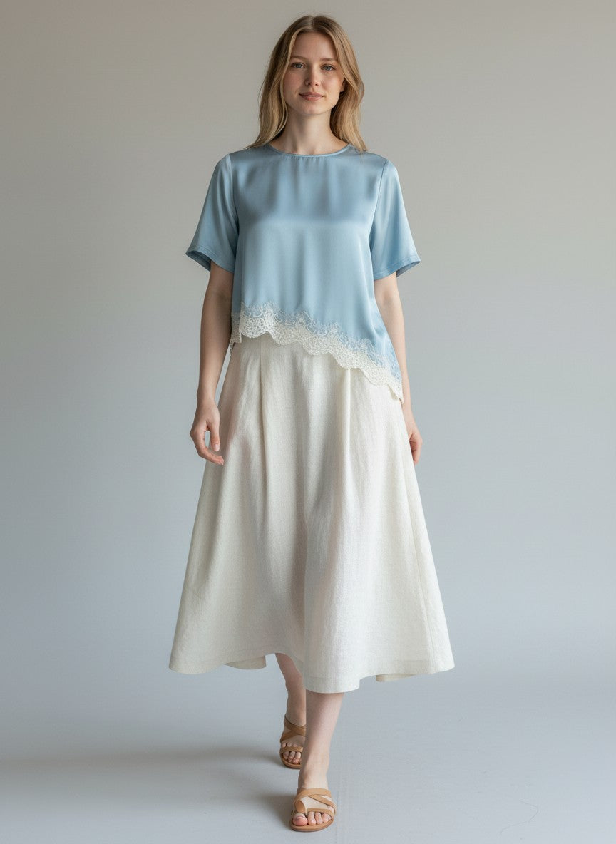 BubiniSegreti Damenbluse aus blauem Satin mit asymmetrischem Saum und cremeweißer Spitzenborte an einem Model
