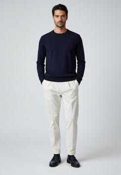 BubiniSegreti Herren-Stoffhose in Off-White mit Bundfalten, kombiniert mit dunkelblauem Pullover und Loafern.