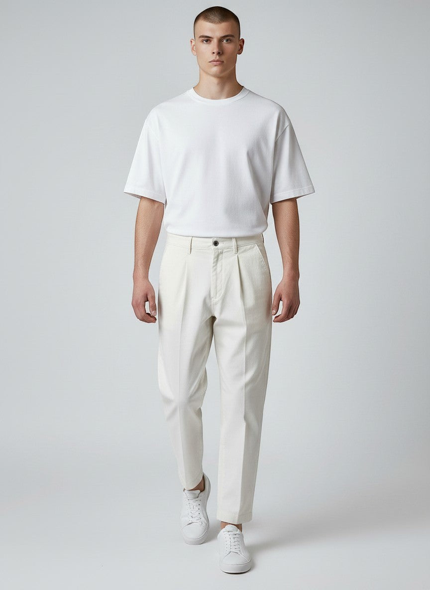 BubiniSegreti Herren-Stoffhose in Off-White mit Bundfalten aus Baumwolle, kombiniert mit weißem T-Shirt und Sneakern.