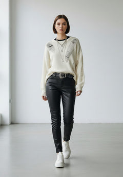 BubiniSegreti Oversized-Strickpullover in Creme mit Distressed-Details, kombiniert mit schwarzer Hose und Sneakern.