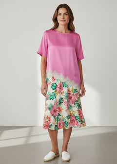 BubiniSegreti Satin-Bluse in Pink mit asymmetrischem Saum, Spitzenbesatz und floralem Rock an einem Model.
