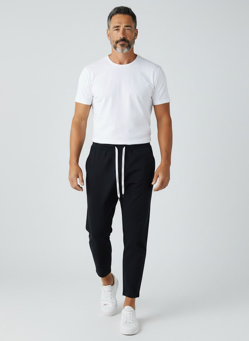 BubiniSegreti Herren-Trainingshose in Schwarz mit Kordelzug, getragen von einem Model mit weißem T-Shirt und Sneakern.