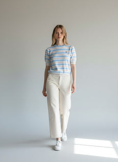 Model wearing a BubiniSegreti short sleeve striped knit sweater in blue, white, and rose with cream trousers.
