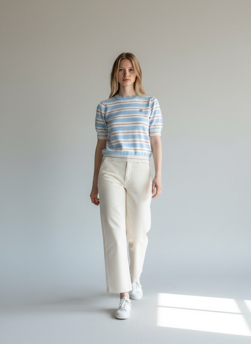 Model wearing a BubiniSegreti short sleeve striped knit sweater in blue, white, and rose with cream trousers.